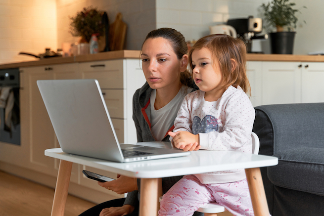 Young parent with small child looking at a laptop together