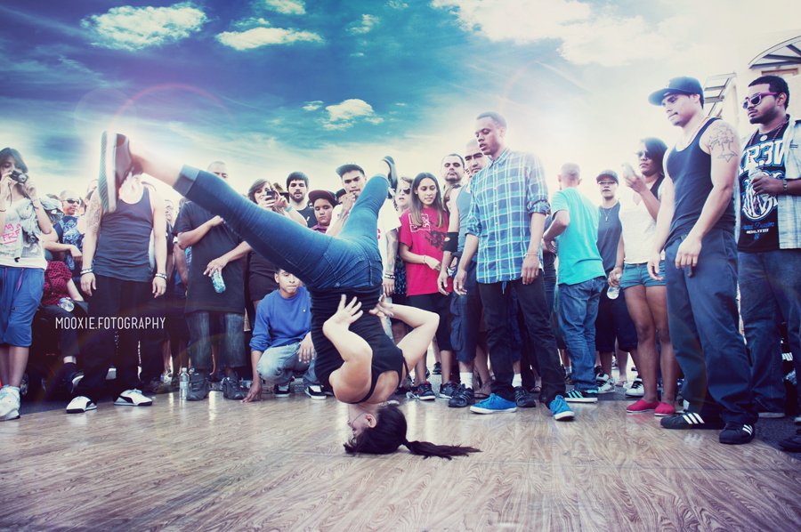 Woman breakdancing on head with crowd of people around