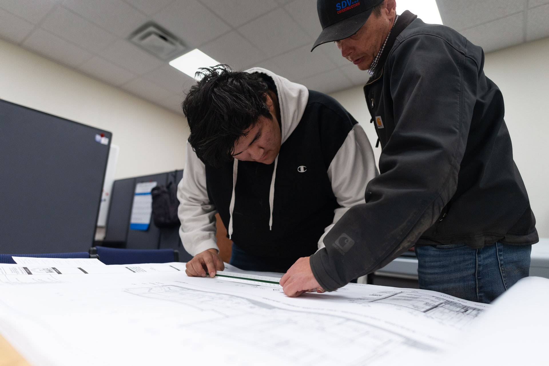 Mentor guiding mentee on creating blueprints before construction.