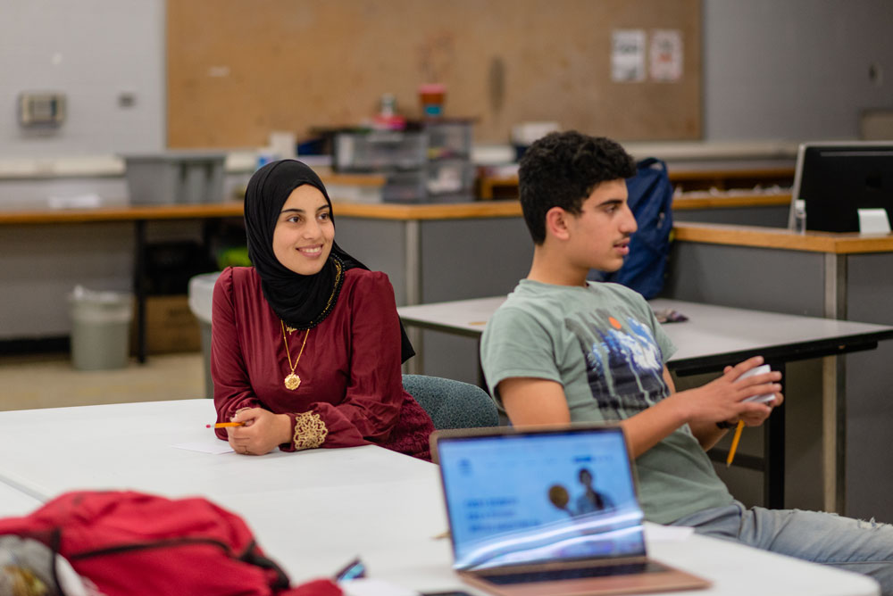 Two student sitting at a desk in their classroom