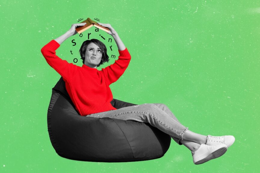 Woman in red sweater sitting in a beanbag chair shakes words out of an open dictionary.