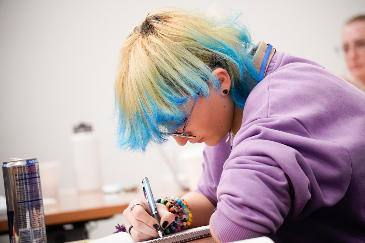 Student with paper an pen, taking a test.