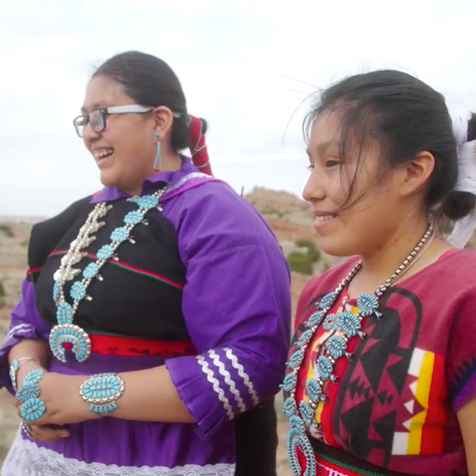 Zuni High School students in traditional Zuni dress looking at something off screen.