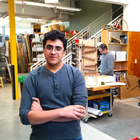 An intern poses in front of a workshop at Explora.