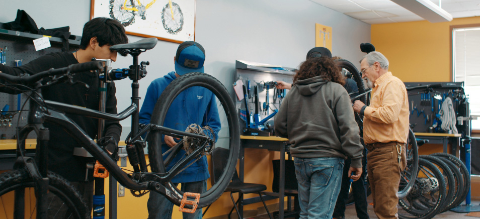 A decorative photo of a group of intern students working on bikes