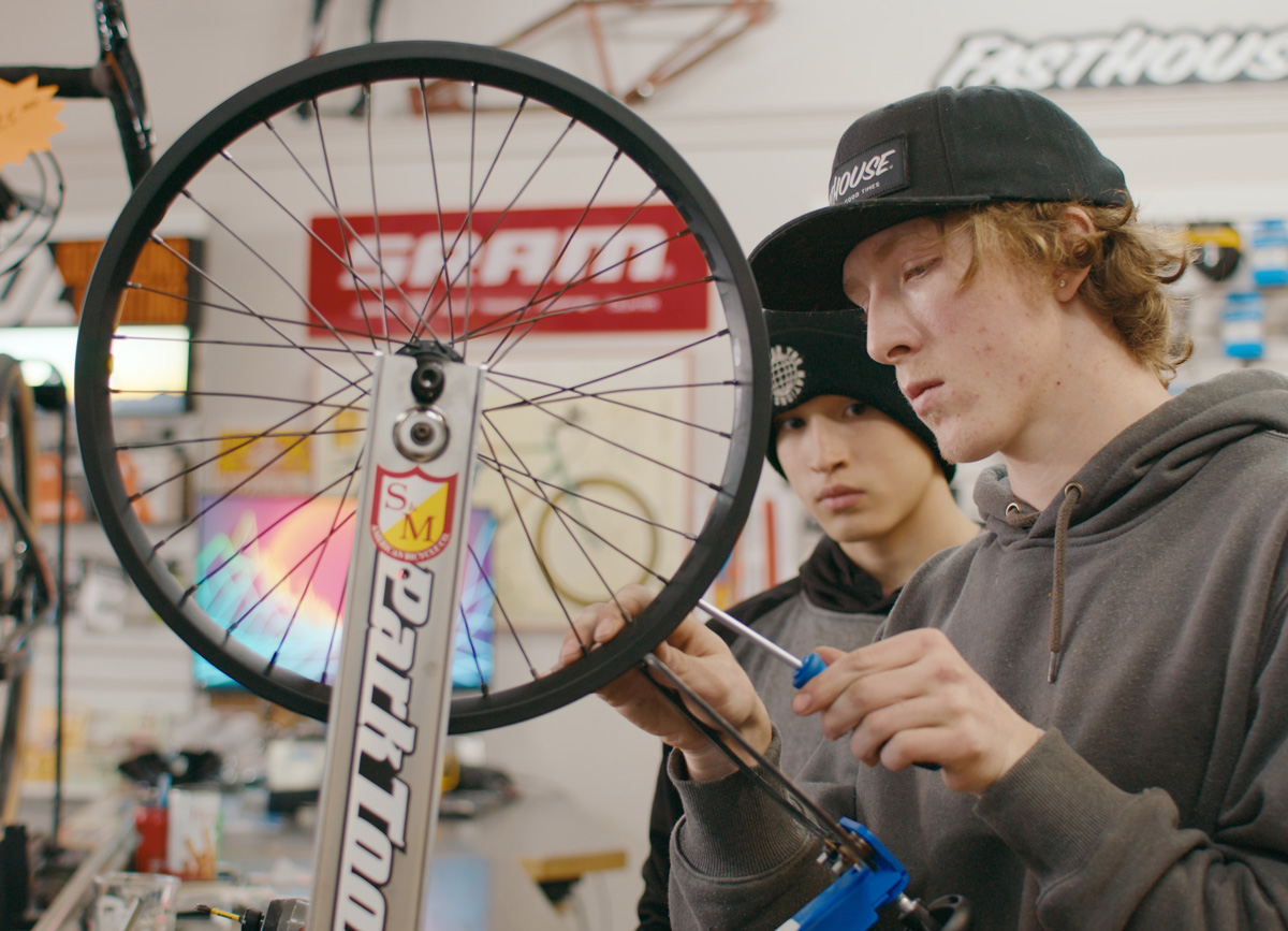 Two students fixing a wheel at a bicycle workshop